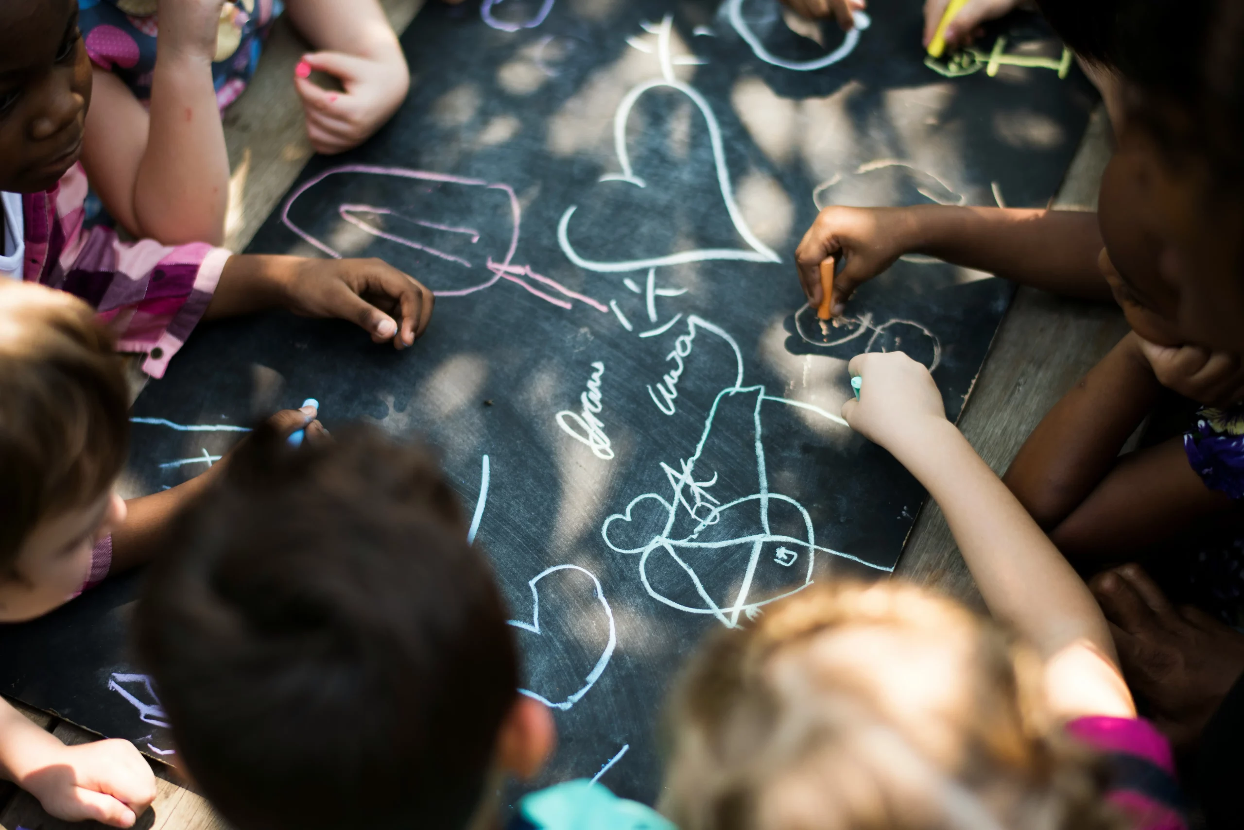 Travail créatif de plusieurs enfants sur un tableau noir