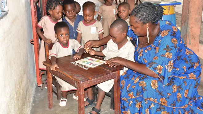 Enseignante accompagnant des enfants avec un matériel pédagogique en classe