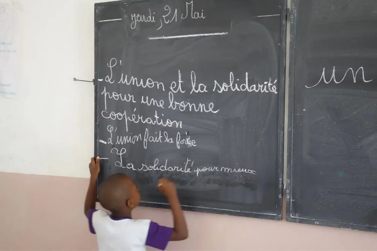 Child in front of a blackboard in a Beninese classroom