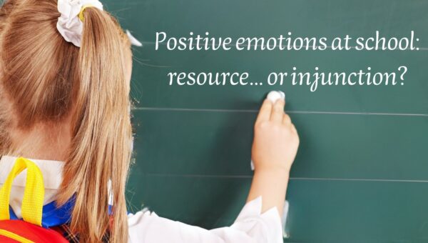 Child writing on a classroom blackboard about positive emotions at school.